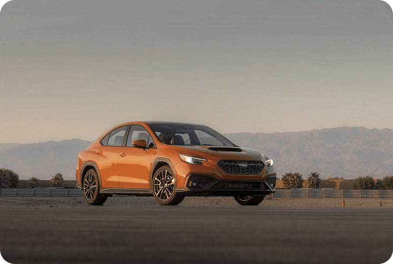 Orange sports car on a road with mountains in background